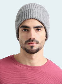 Man wearing a gray knit beanie and pink shirt on a white background