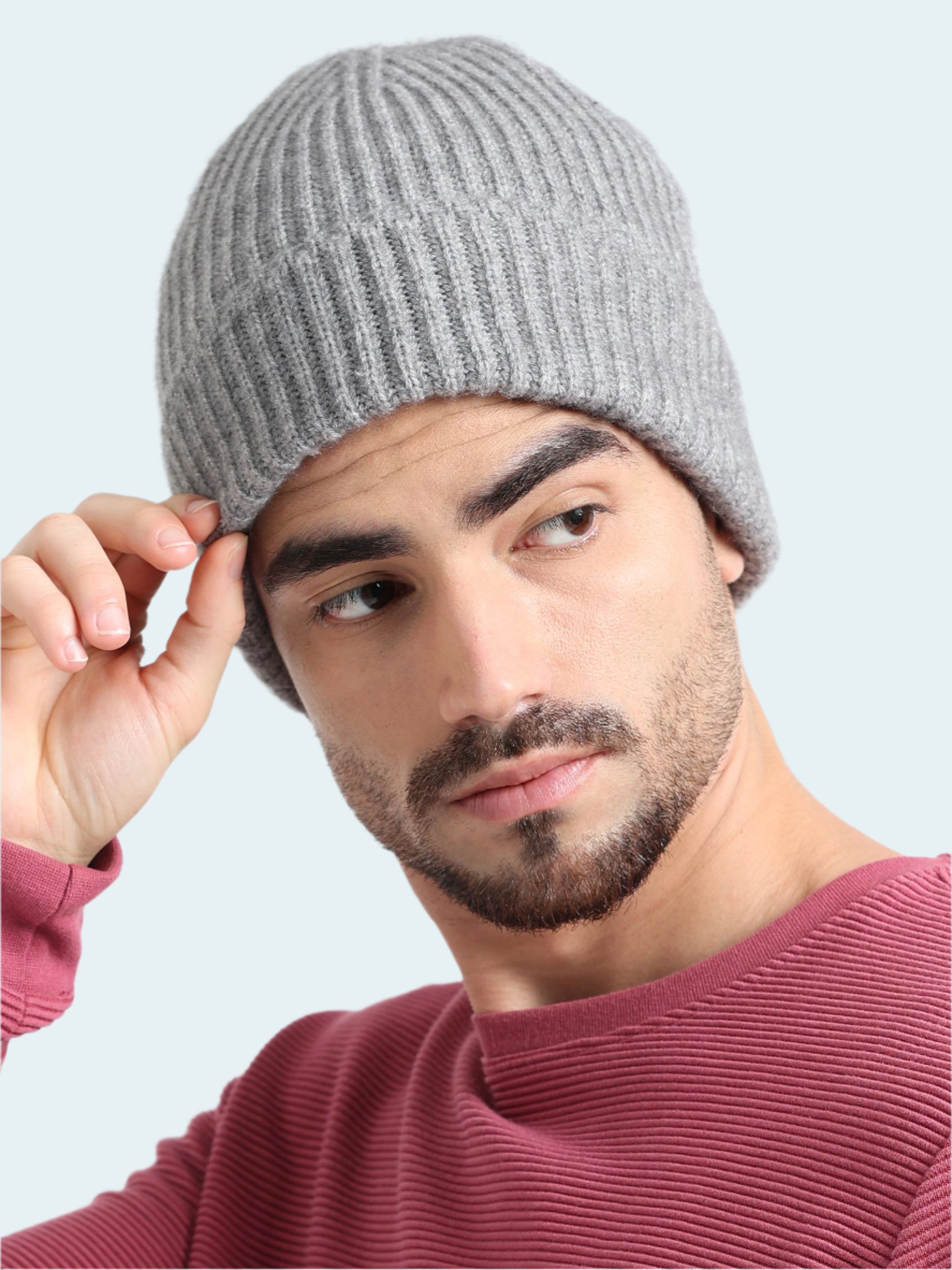 Man wearing a gray knit beanie against a plain background