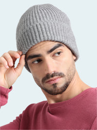 Man wearing a gray knit beanie against a plain background