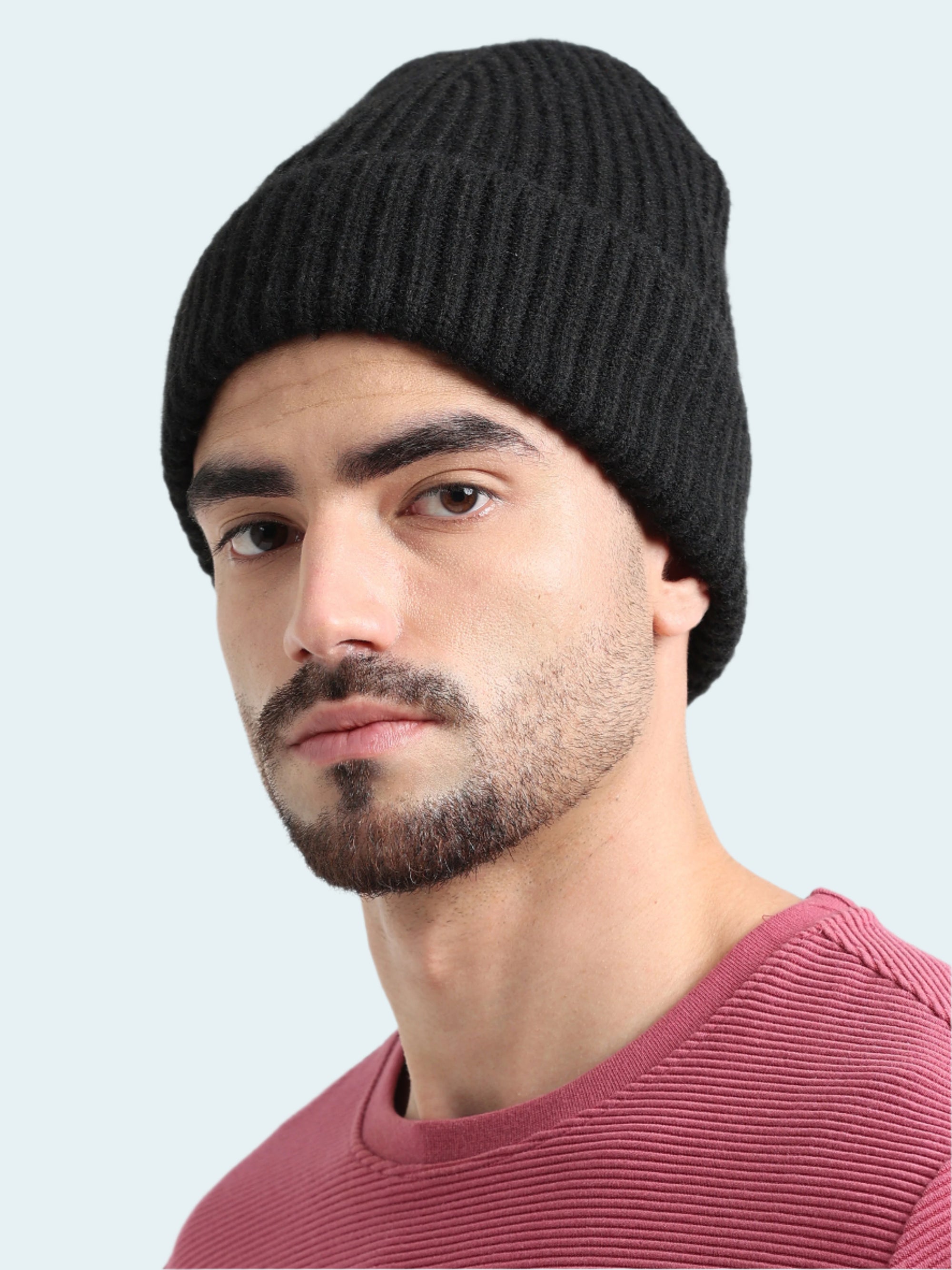 Man wearing a black knit beanie and maroon shirt against a white background