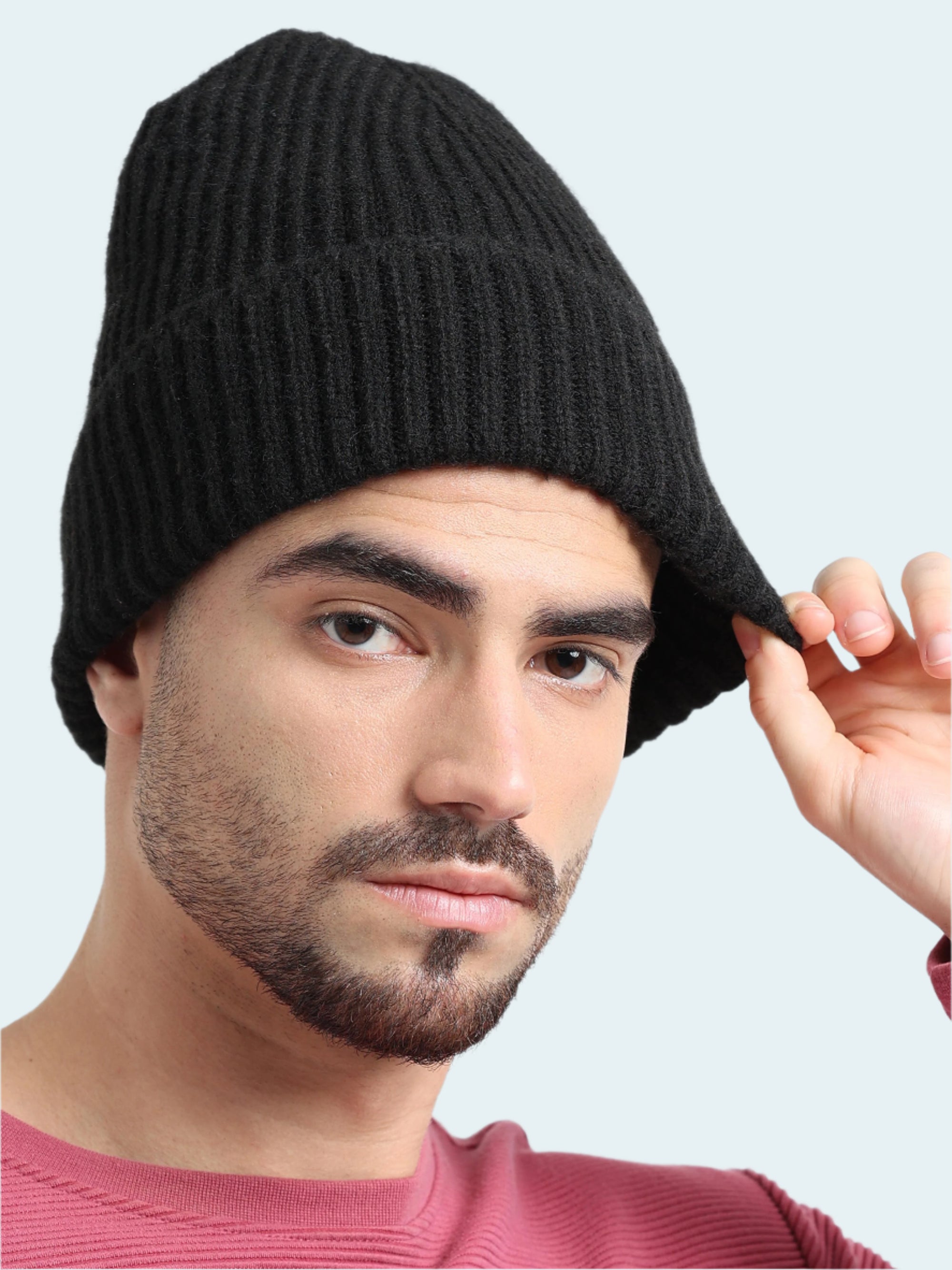 Man wearing a black knit beanie against a plain background