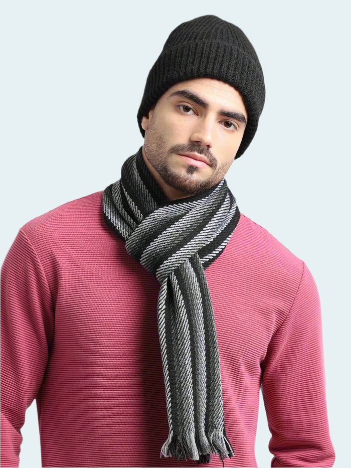 Man wearing a black knit beanie and gray scarf against a light gray background