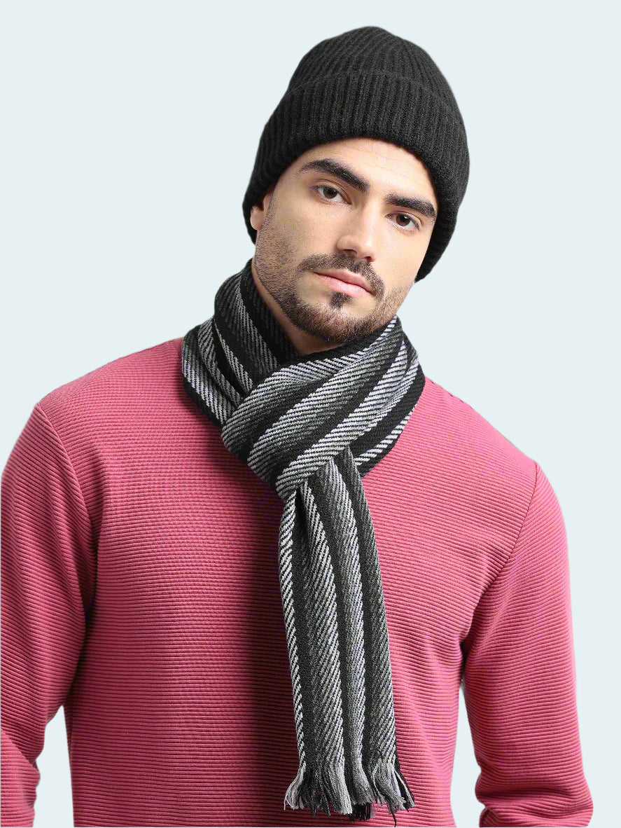 Man wearing a black knit beanie and gray scarf against a light gray background
