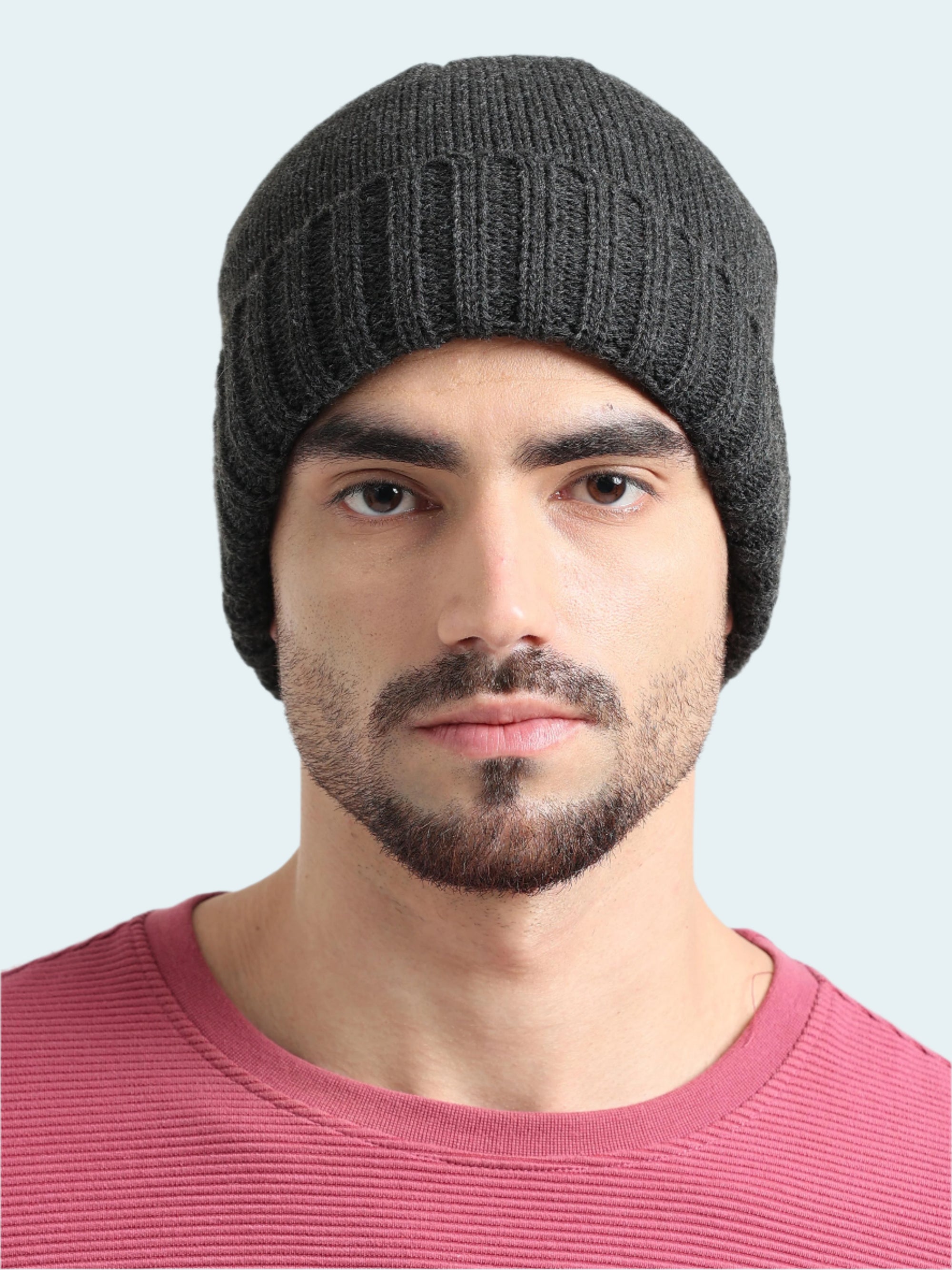 Man wearing a dark gray knit beanie against a plain background