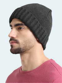 Man wearing a dark gray knit beanie against a white background