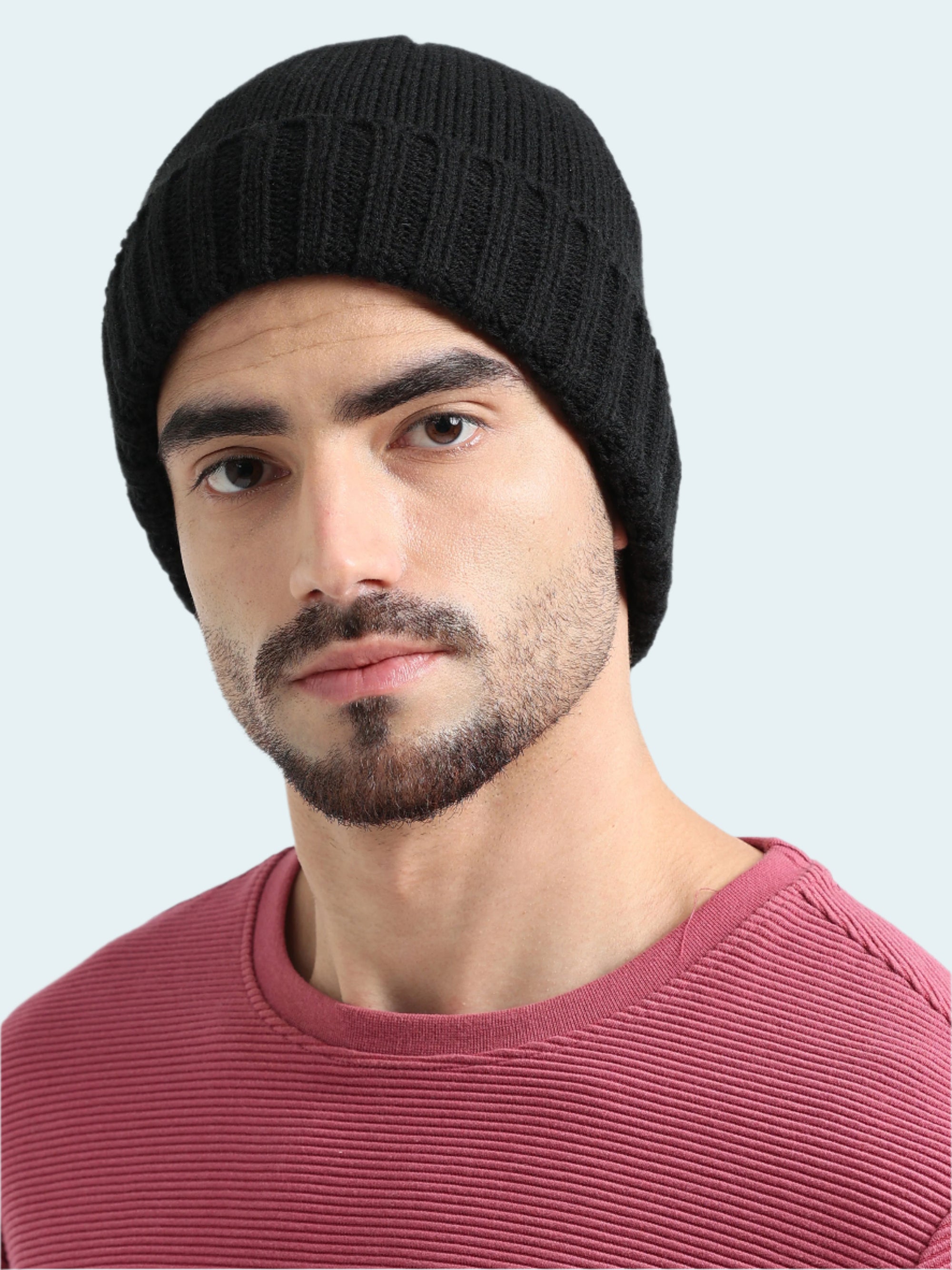 Man wearing a black beanie and pink shirt against a white background