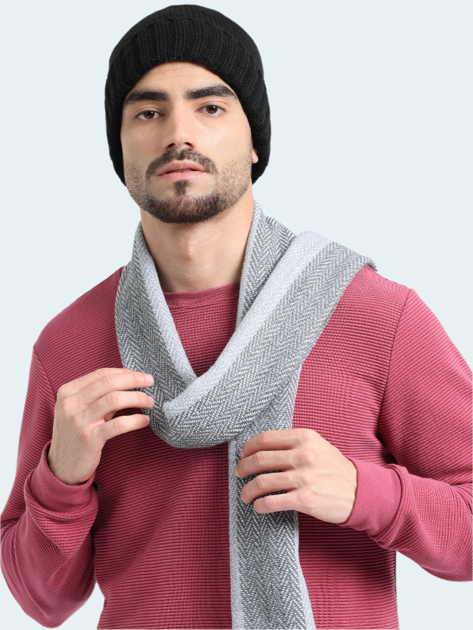 Man wearing a black beanie and gray scarf against a white background