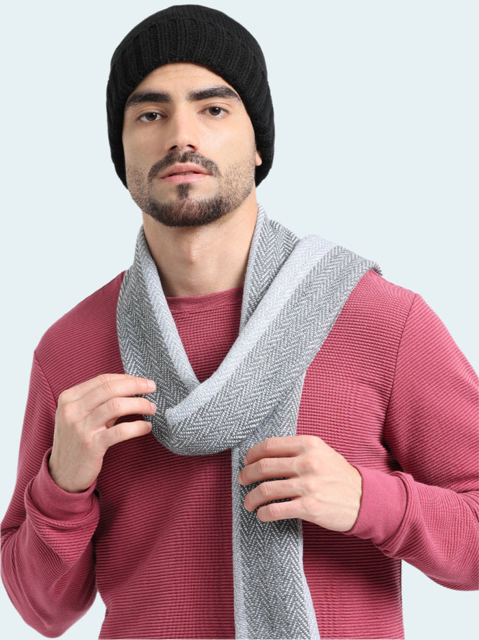 Man wearing a black beanie and gray scarf against a white background