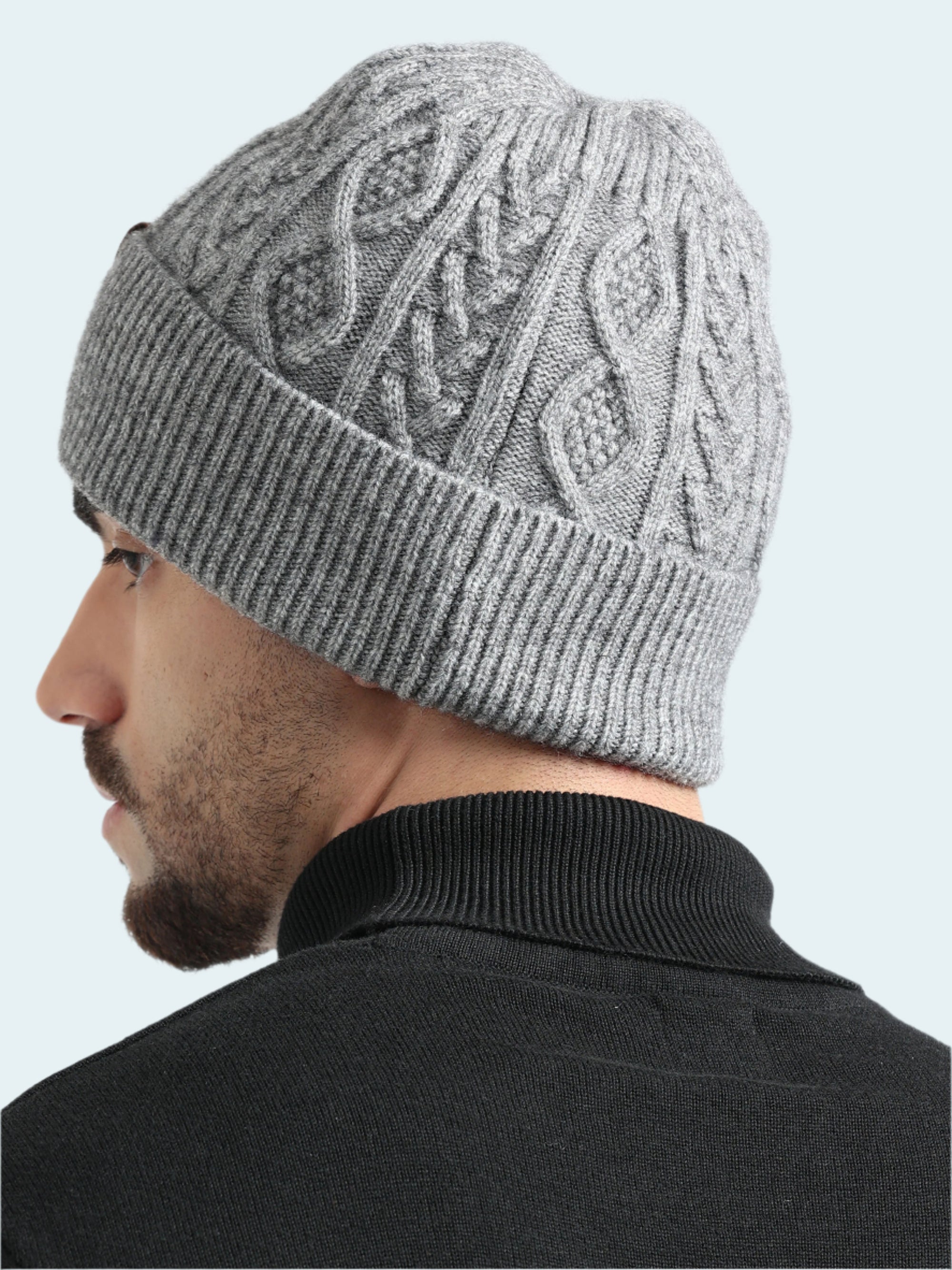 Person wearing a gray knitted beanie with a white background