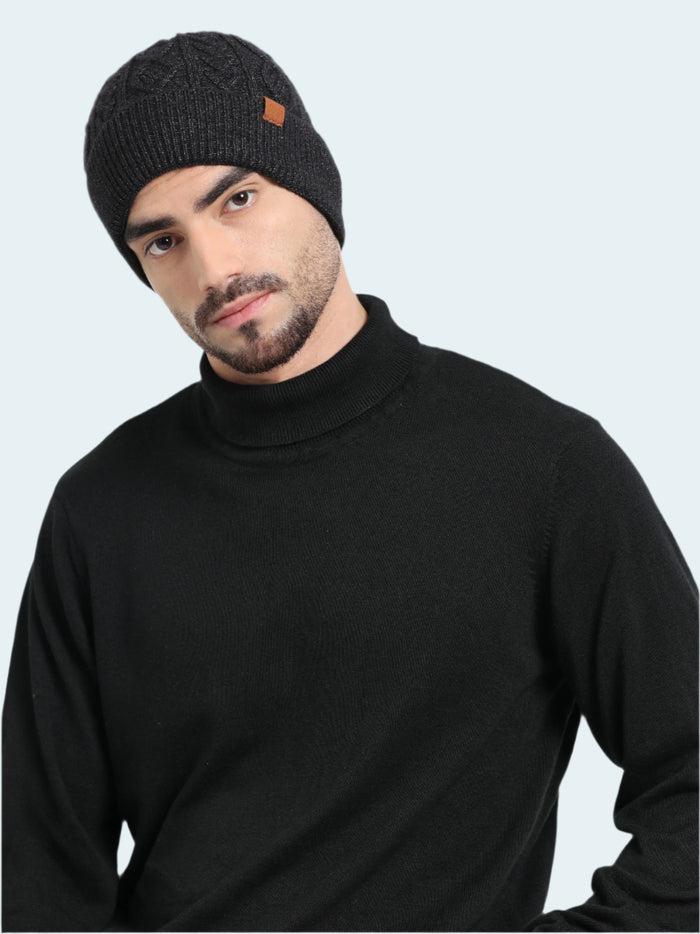 Man wearing a black knit beanie and black turtleneck sweater on a white background