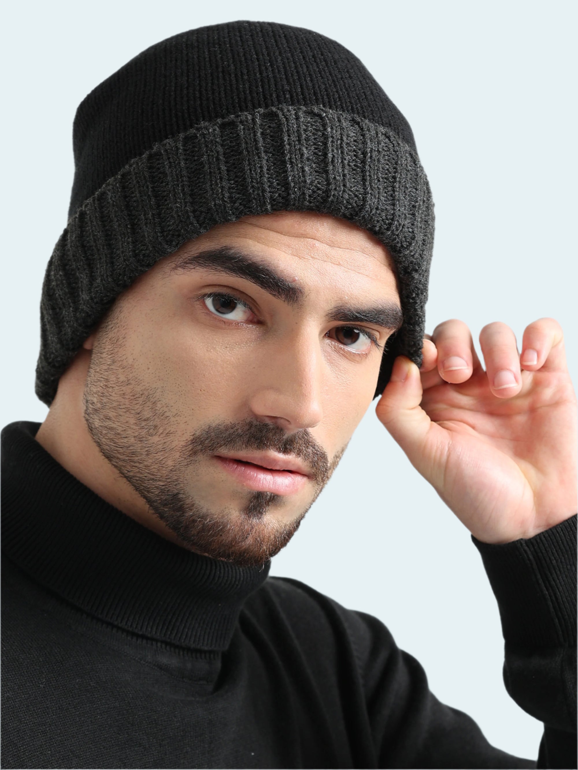 Man wearing a black knit beanie against a light gray background