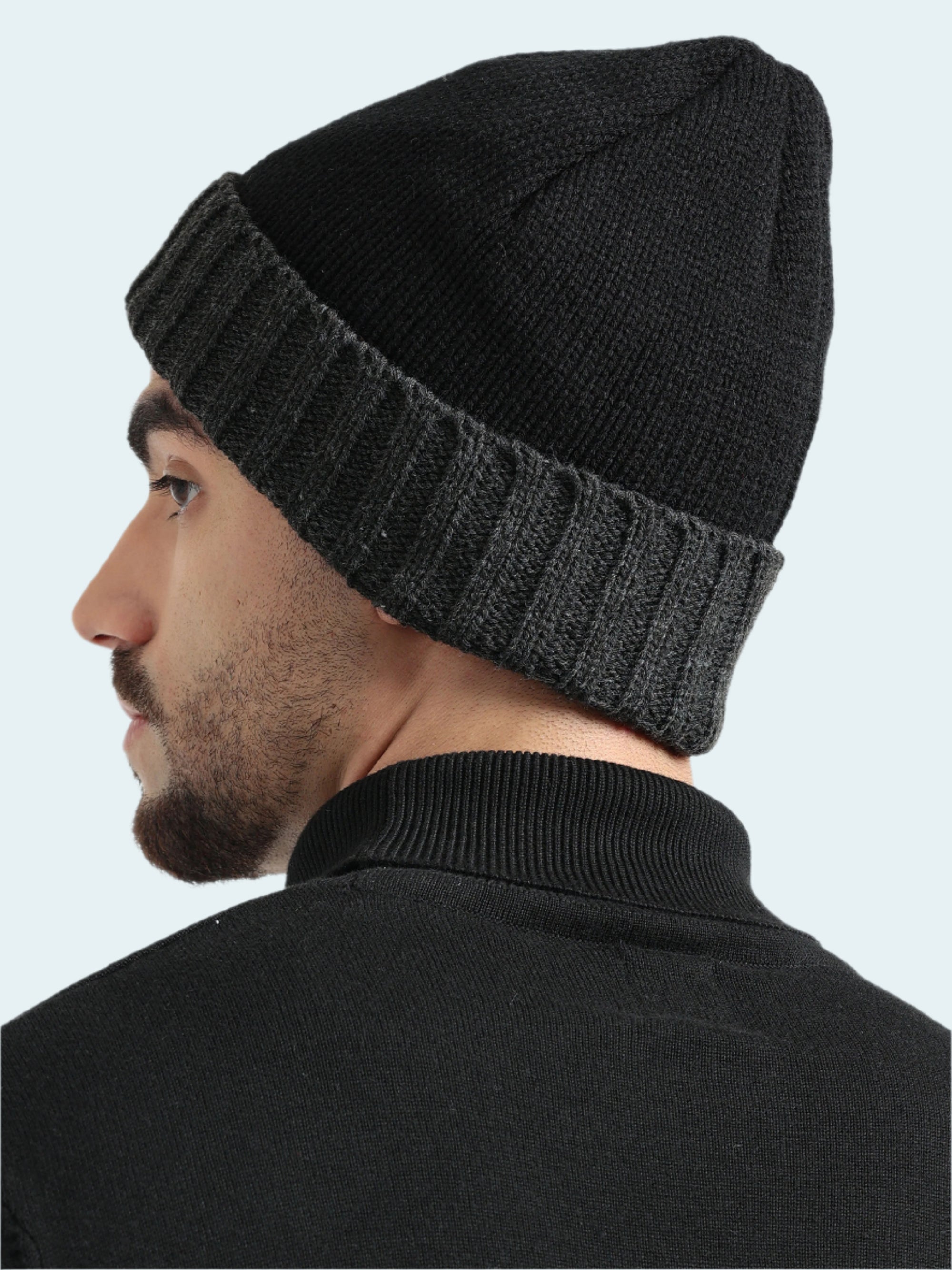 Man wearing a black knit beanie against a white background