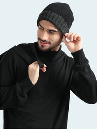 Man wearing a black knit beanie and black hoodie against a light gray background