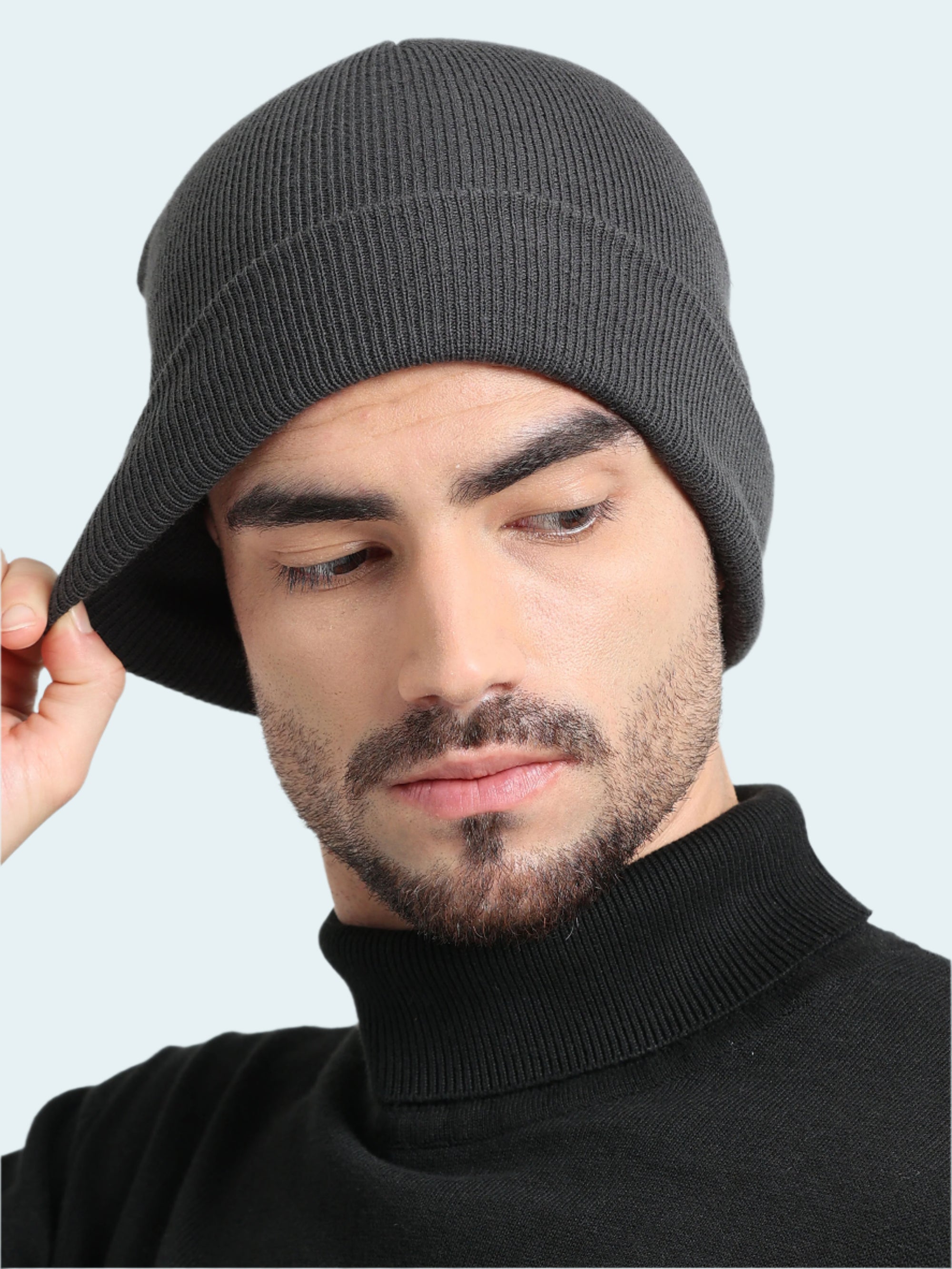 Man wearing a gray knit beanie against a plain background