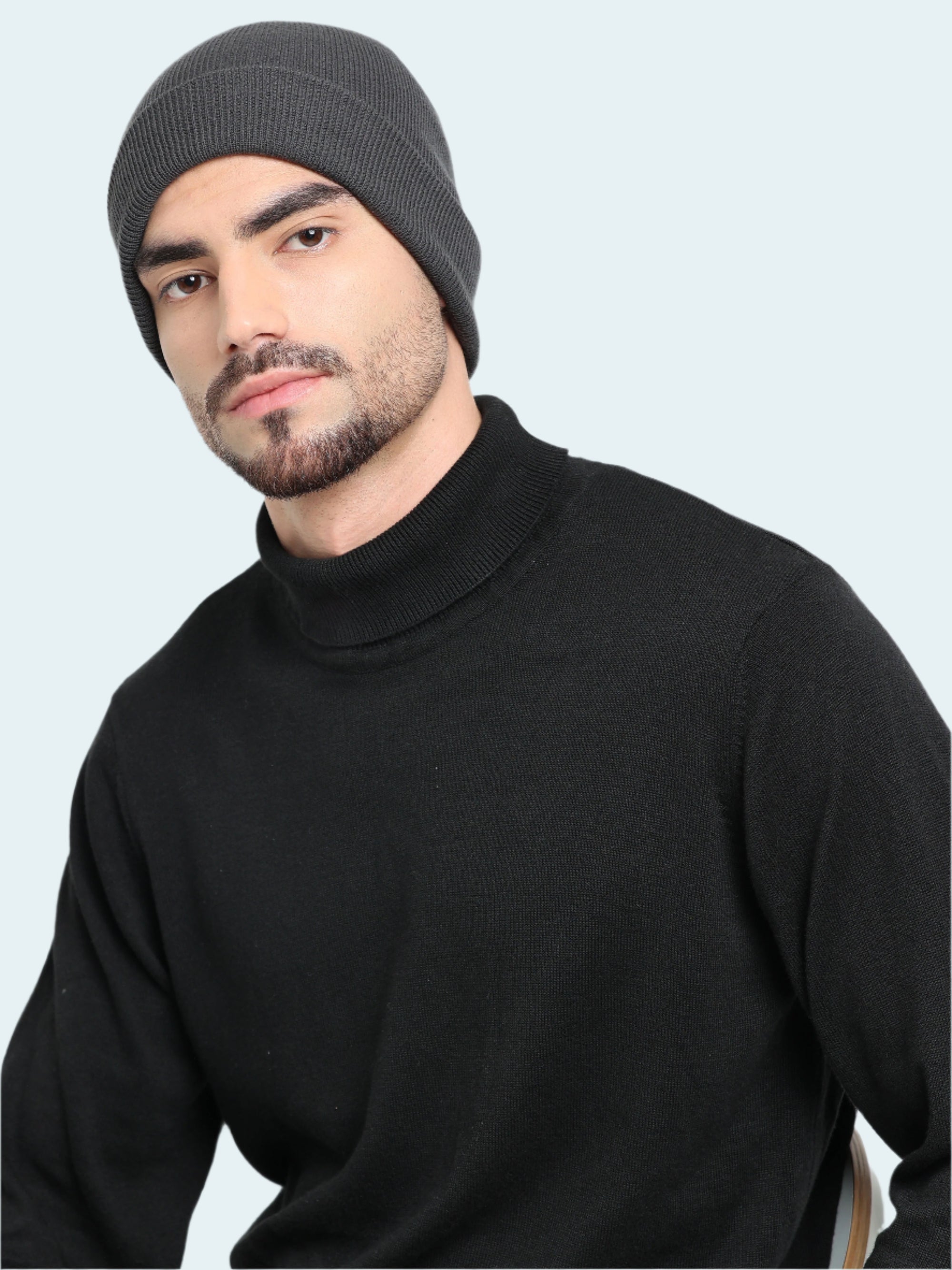 Man wearing a black turtleneck sweater and gray beanie against a white background