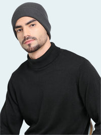 Man wearing a black turtleneck sweater and gray beanie against a white background