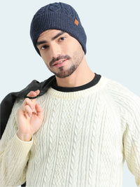 Man wearing a navy knit beanie and cream sweater against a light background