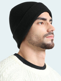 Man wearing a black knit beanie and white sweater on a light gray background