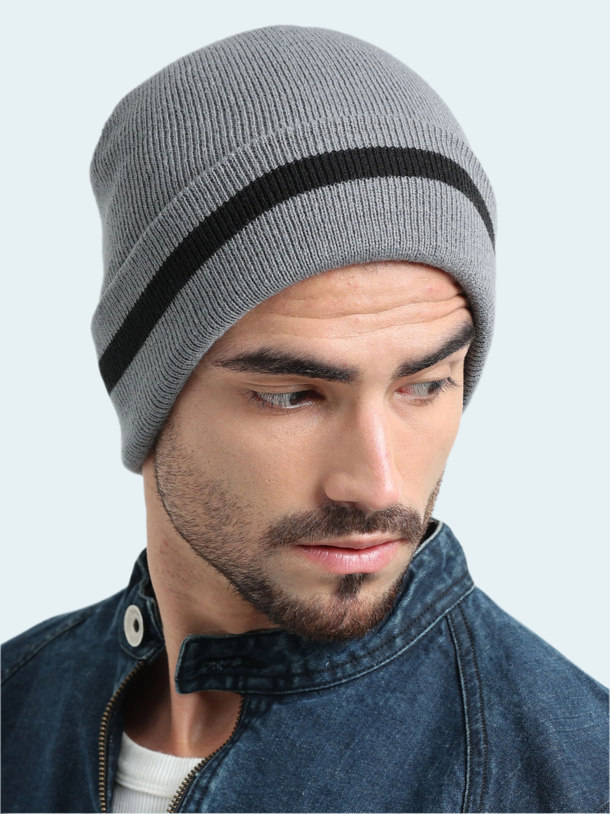 Man wearing a gray knit beanie with a black stripe on a light gray background