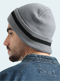 Person wearing a gray knit beanie with a black stripe on a white background