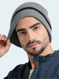 Man wearing a gray knit beanie with a black stripe on a light gray background