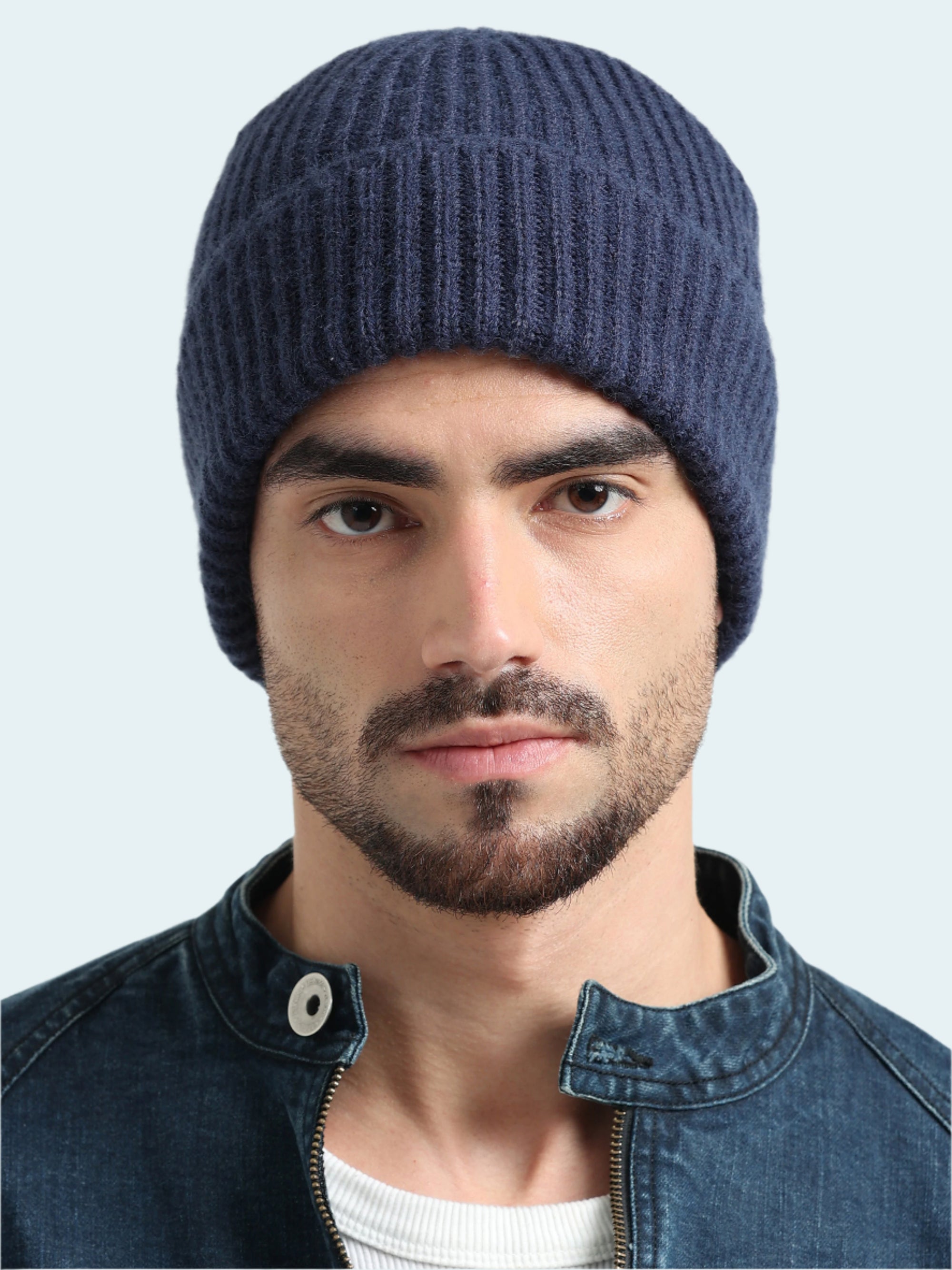 Man wearing a blue knit beanie and denim jacket on a white background
