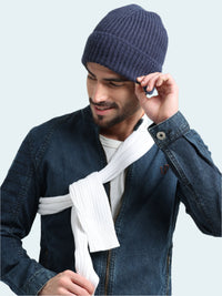 Man wearing a blue knit beanie and denim jacket with a white scarf, on a light gray background