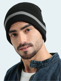 Man wearing a black beanie with gray stripes on a light gray background
