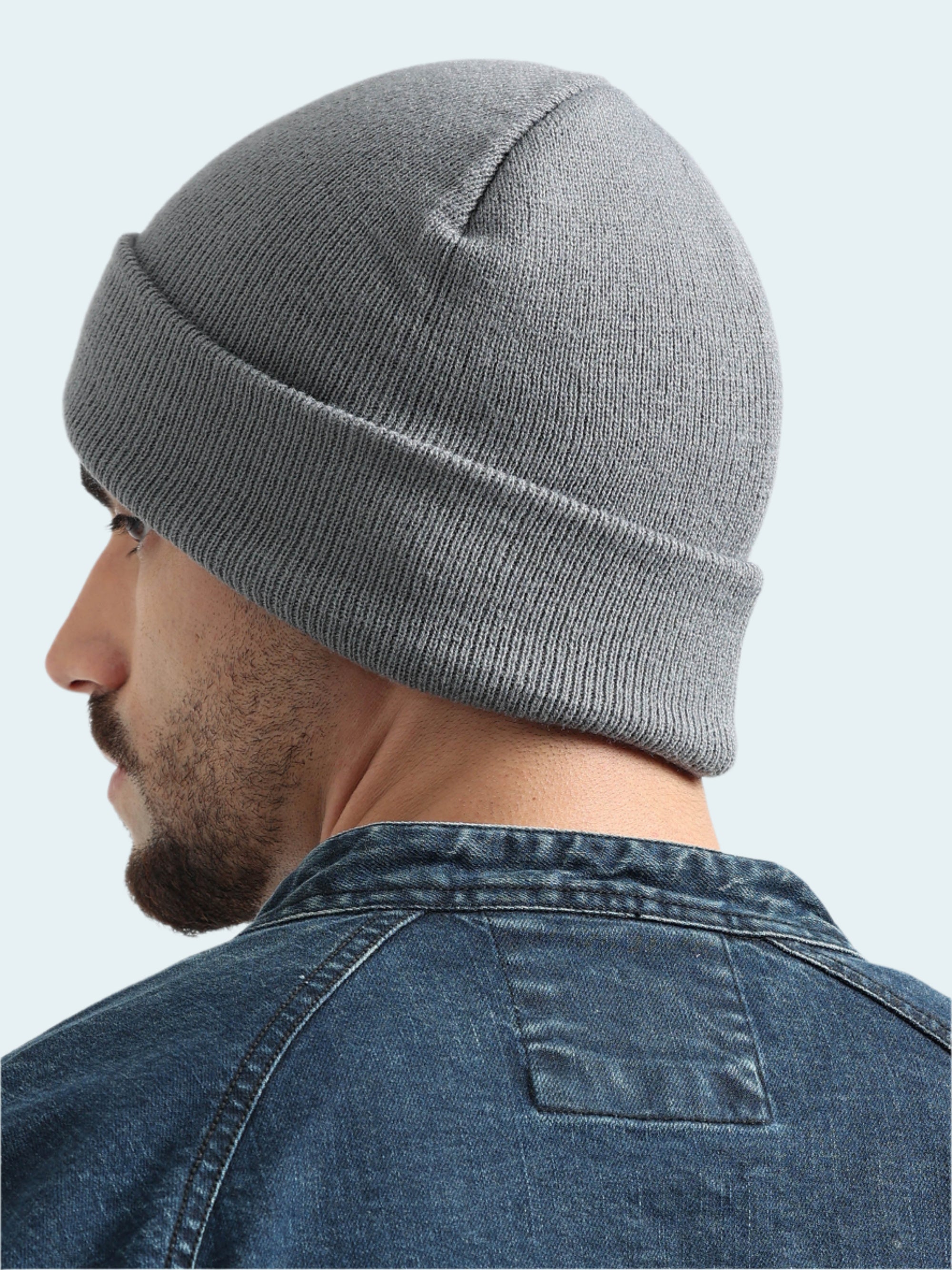 Person wearing a gray beanie and denim jacket on a white background