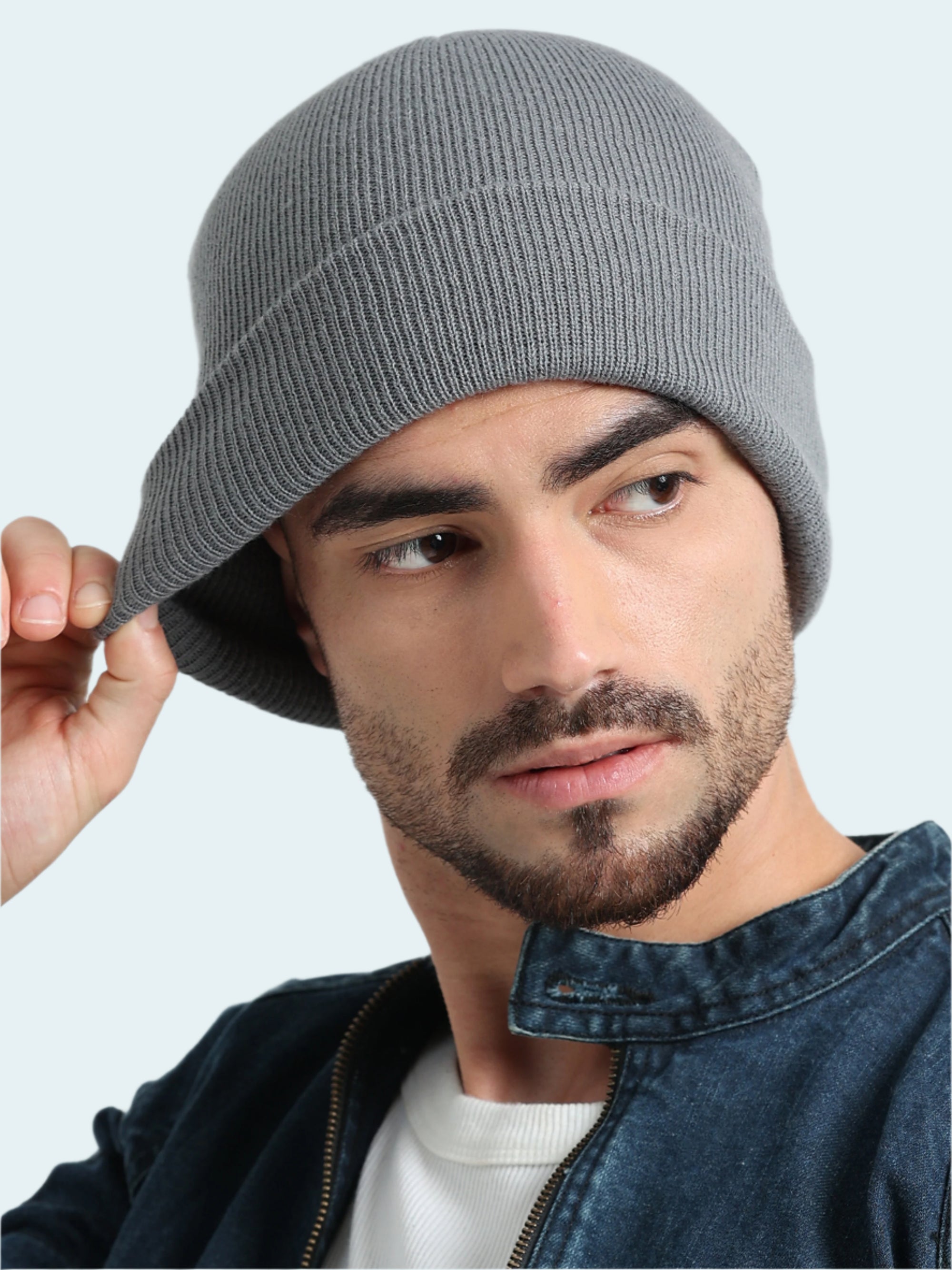 Man wearing a gray knit beanie against a plain background