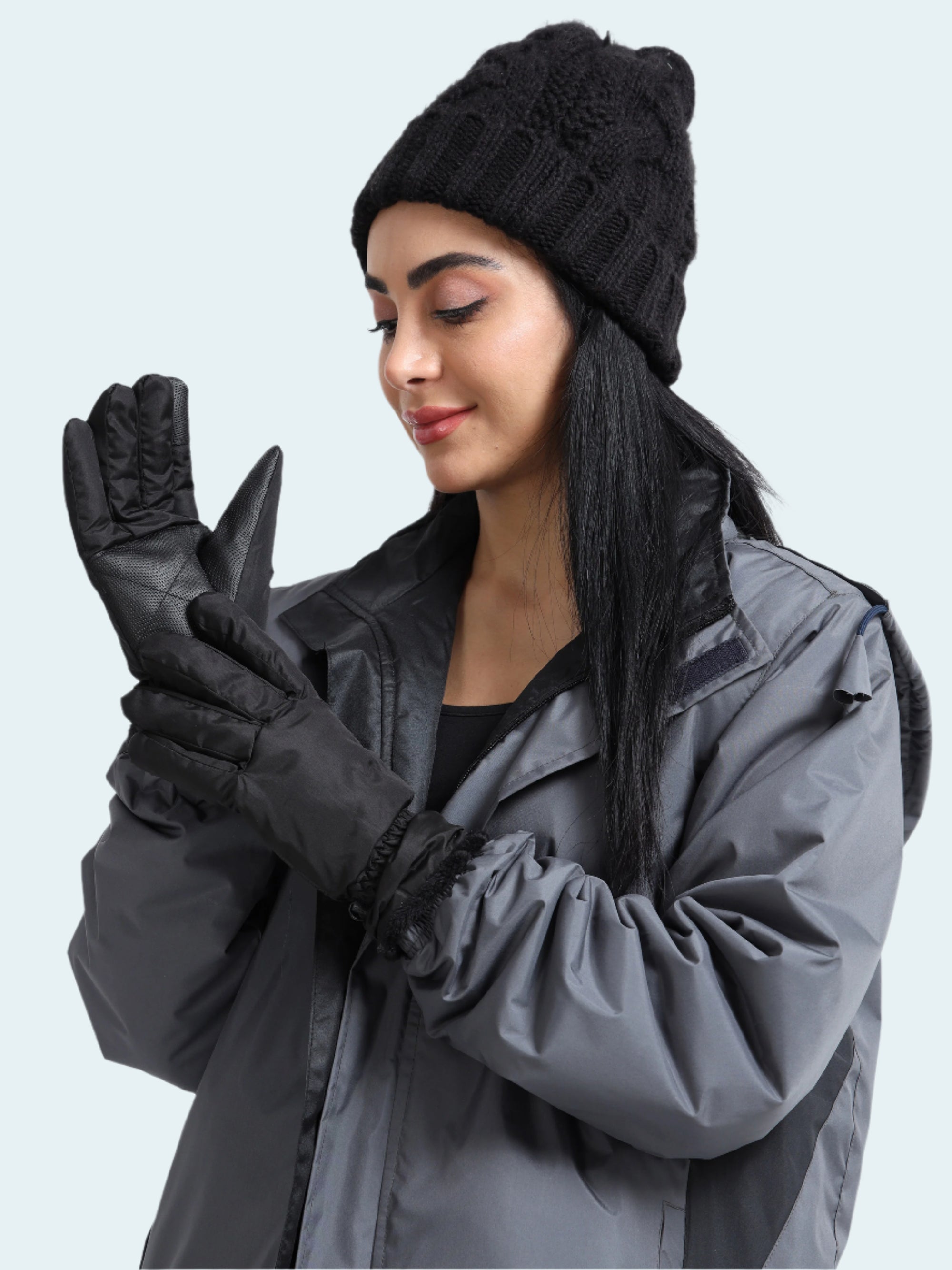 Woman wearing a black knit hat, gray jacket, and black gloves on a white background