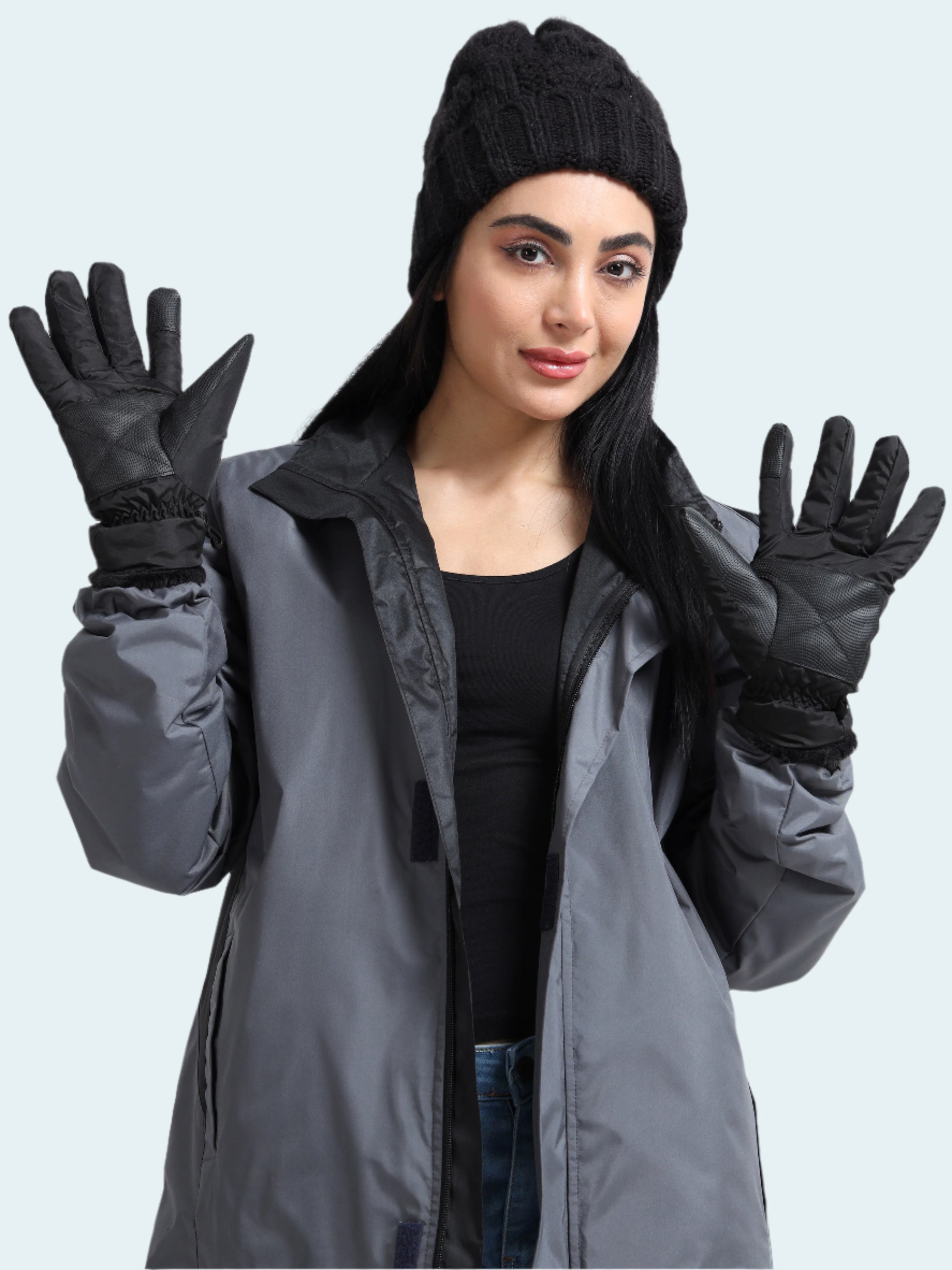 Woman wearing a gray coat, black beanie, and gloves on a white background