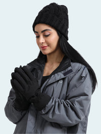 Woman wearing a gray coat, black beanie, and gloves on a white background