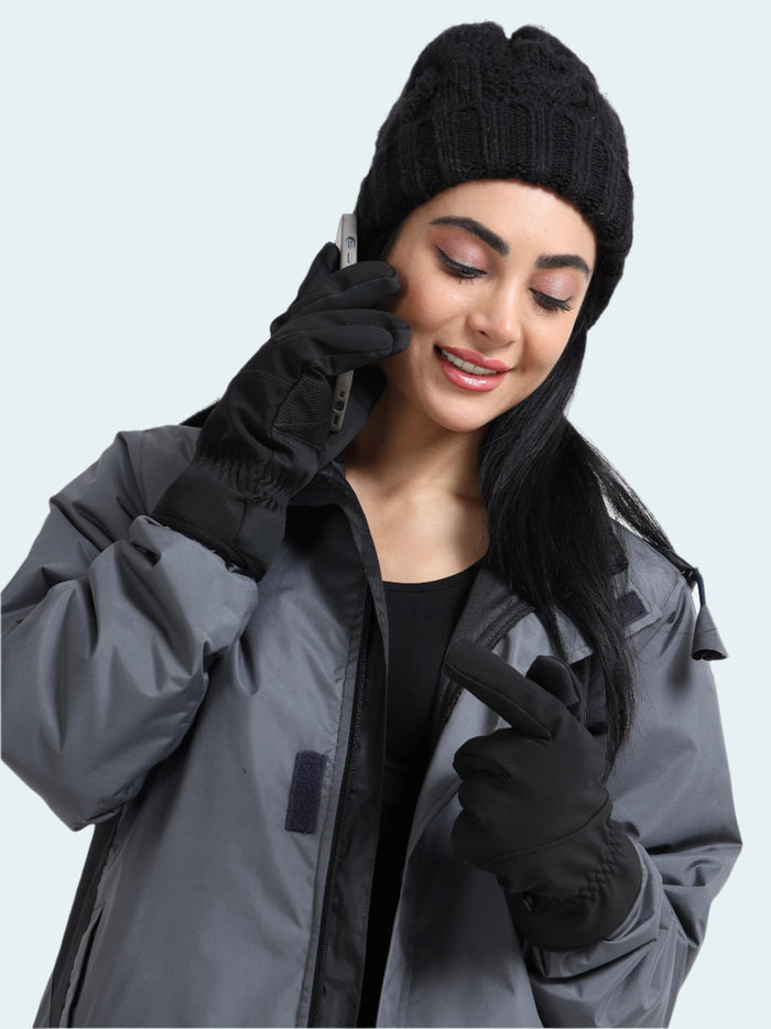 Woman wearing a gray jacket, black beanie, and gloves on a white background