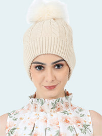 Woman wearing a beige knitted beanie with a pom-pom on a white background