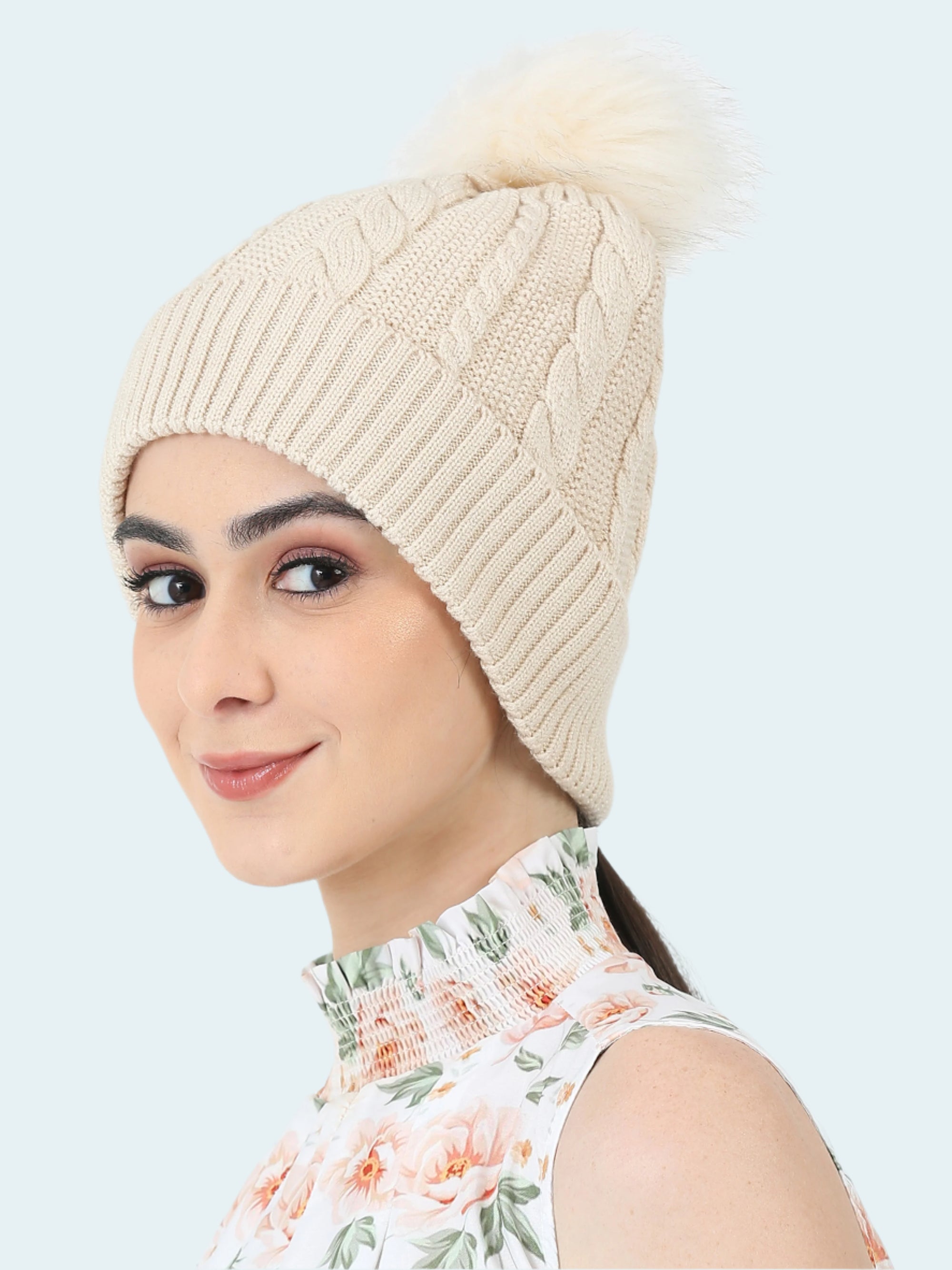 Woman wearing a beige knitted beanie with a pom-pom on a white background