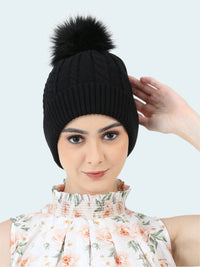 Black knit beanie with a pom-pom worn by a person on a white background