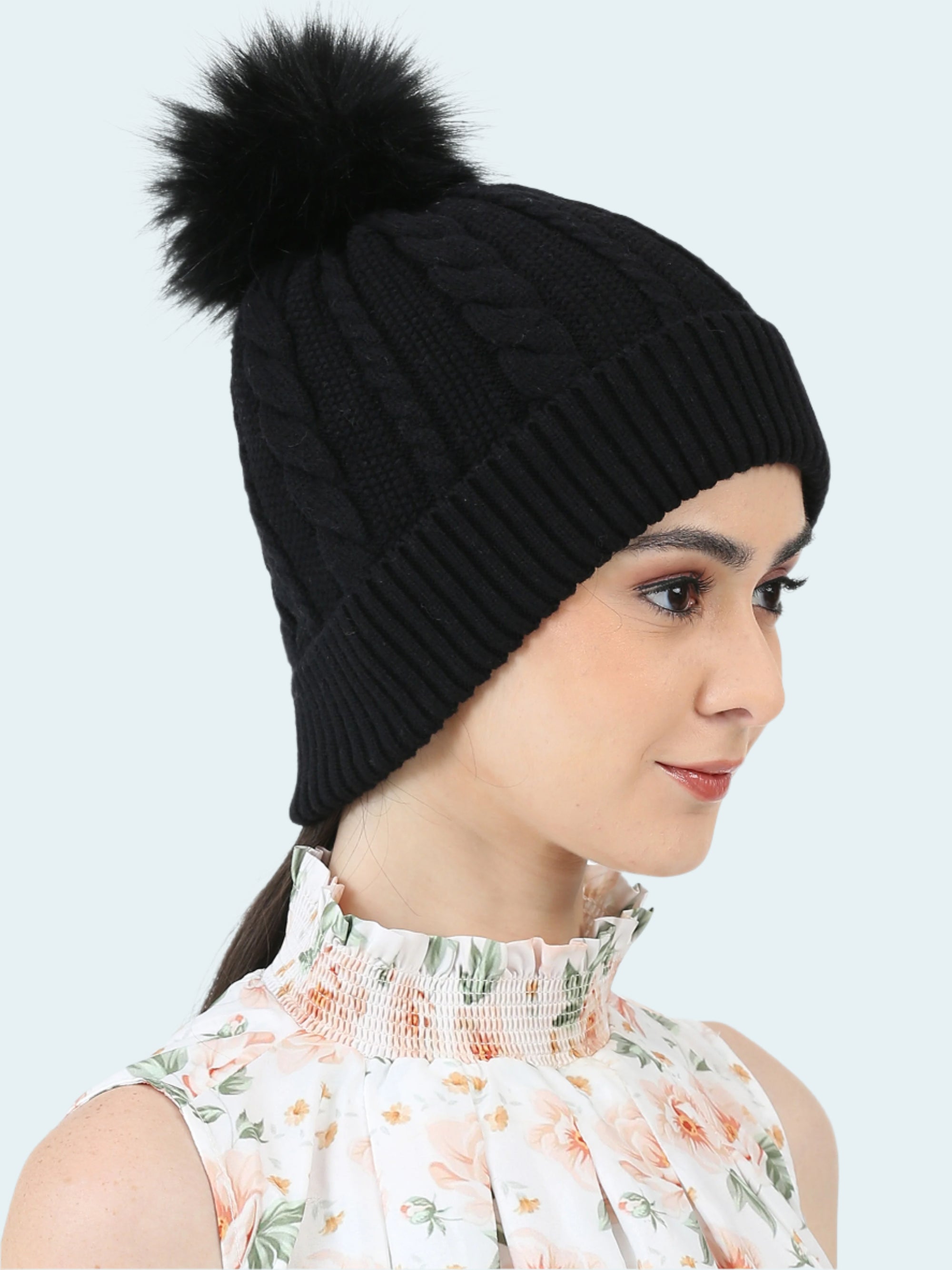 Black knit beanie with a pom-pom worn by a model on a white background