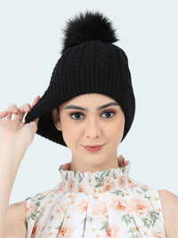 Woman wearing a black knit beanie with a pom-pom on a white background
