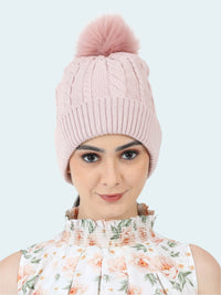 Pink knitted beanie with a pom-pom worn by a person on a white background