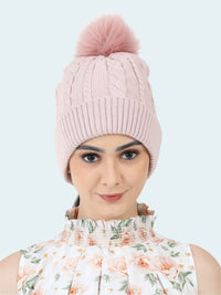 Pink knitted beanie with a pom-pom worn by a person on a white background