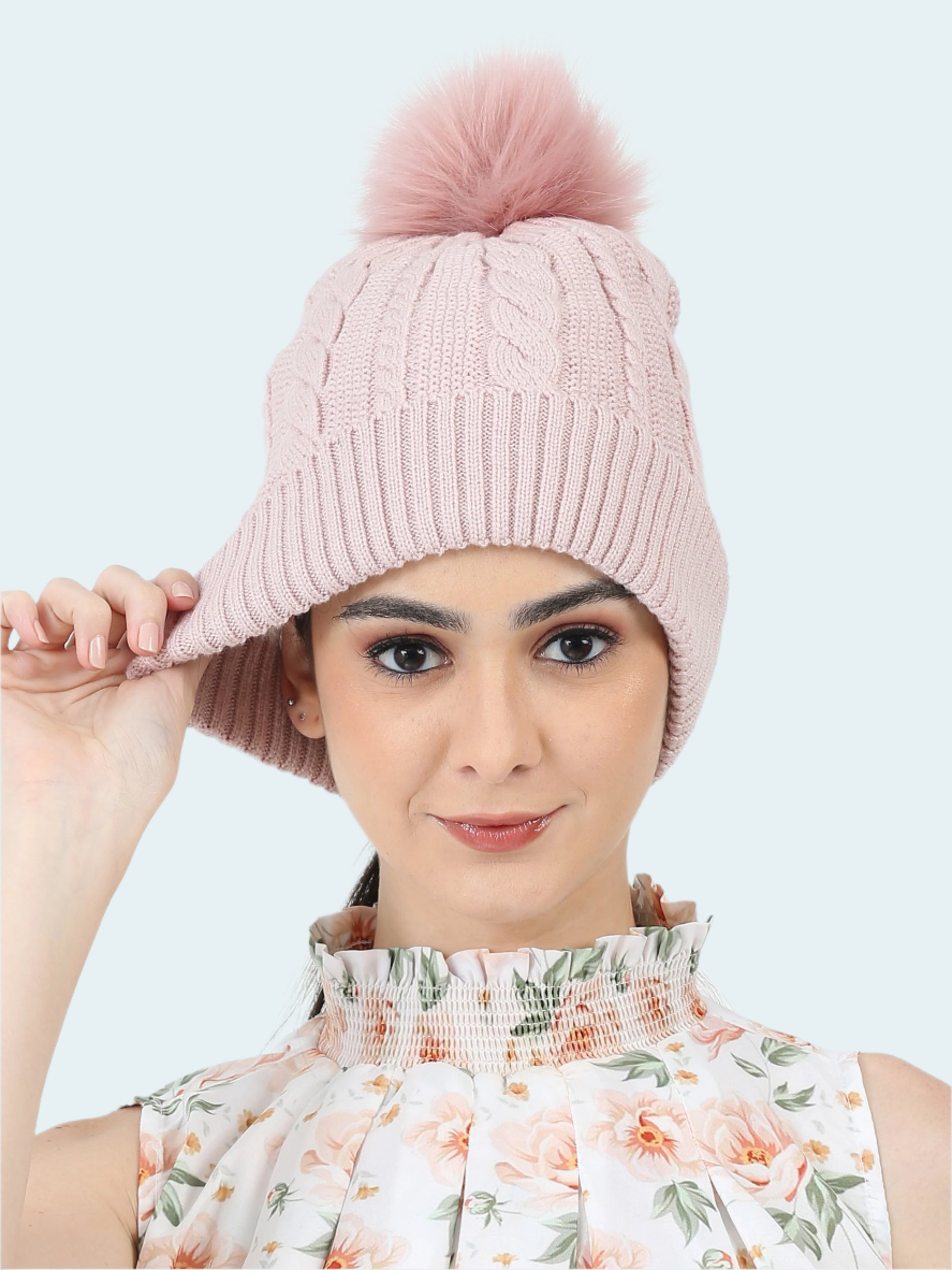 Woman wearing a pink knitted beanie with a pom-pom on a white background