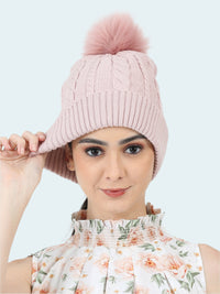 Woman wearing a pink knitted beanie with a pom-pom on a white background