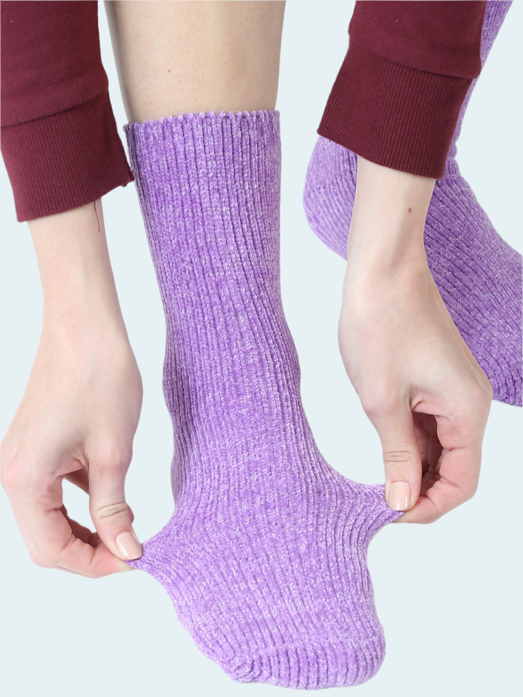 Person wearing purple socks with hands adjusting them on a white background