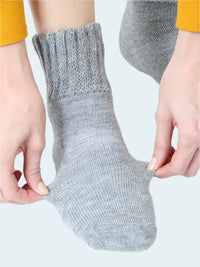 Gray sock being worn on a white background