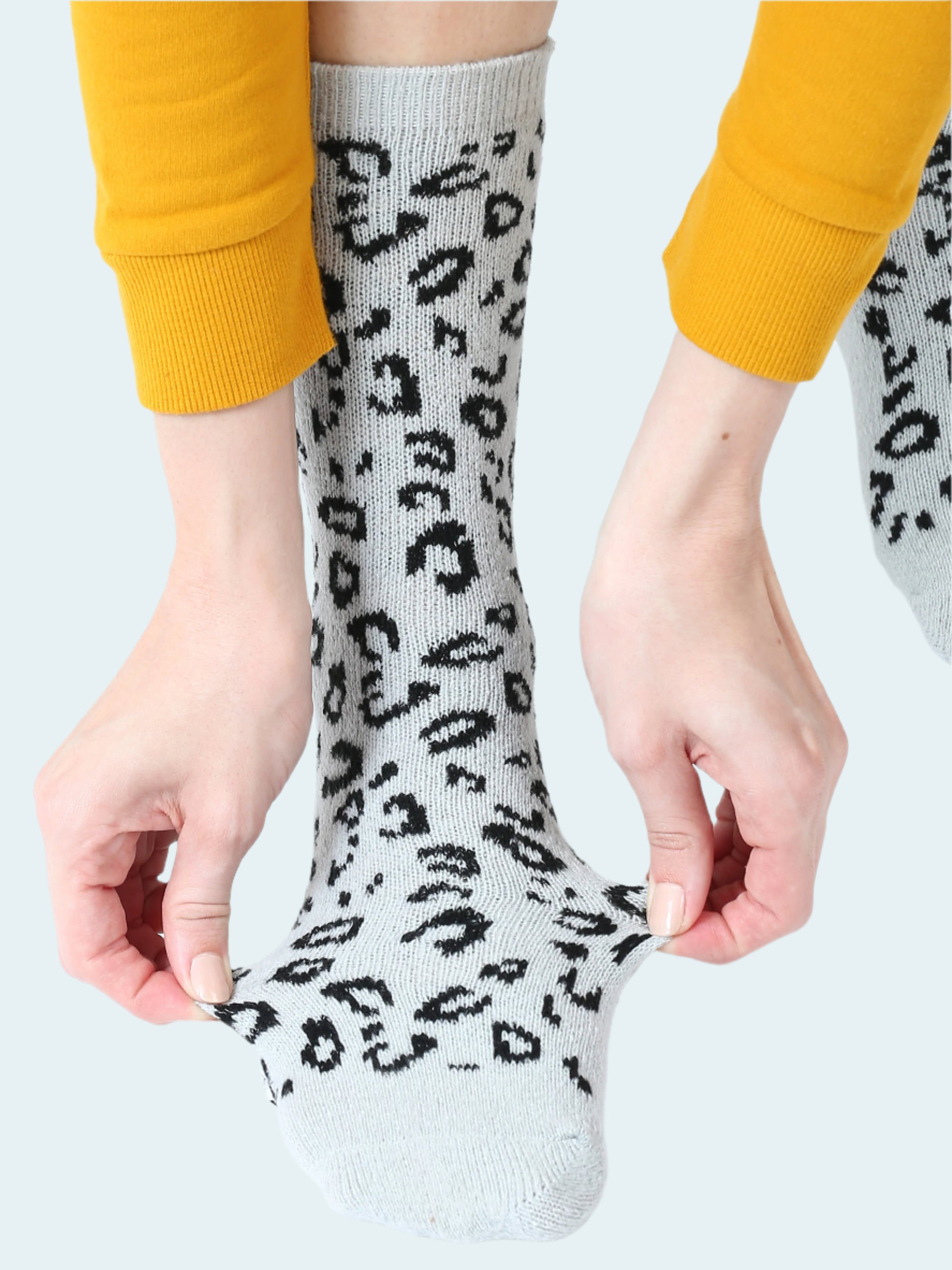 Person wearing light gray socks with black leopard print pattern, paired with yellow pants.