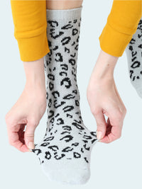 Person wearing light gray socks with black leopard print pattern, paired with yellow pants.