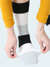 Person wearing striped knee-high socks with yellow pants on a white background