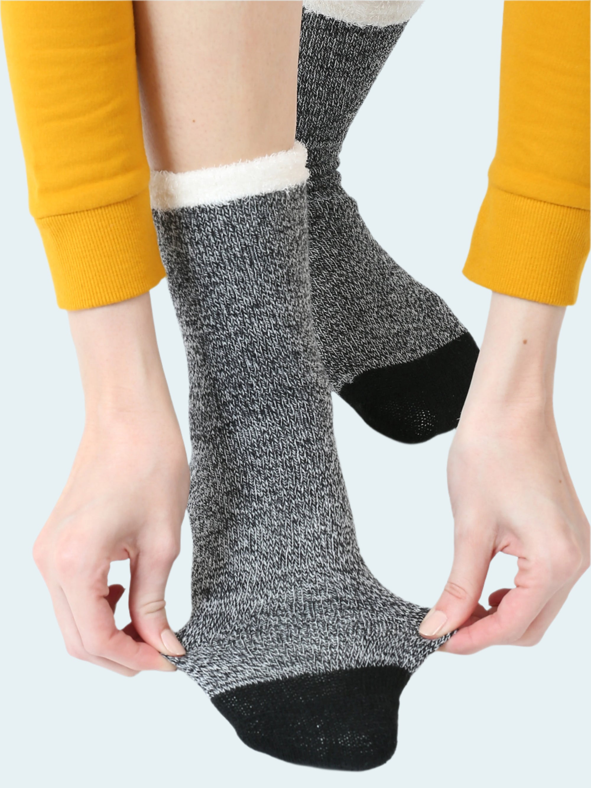 Person wearing gray socks with black toes and cuffs on a white background