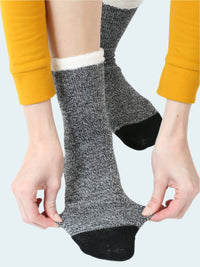 Person wearing gray socks with black toes and cuffs on a white background